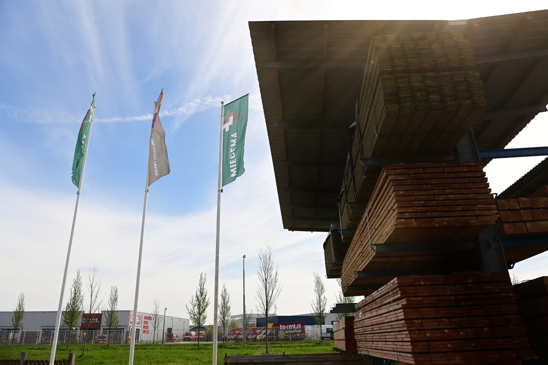 Overdekte houtopslag met Miedema-vlaggen op het terrein in Leeuwarden